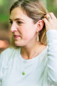 Woman wearing mountain-inspired topographic jewelry ring and pendant outdoors.